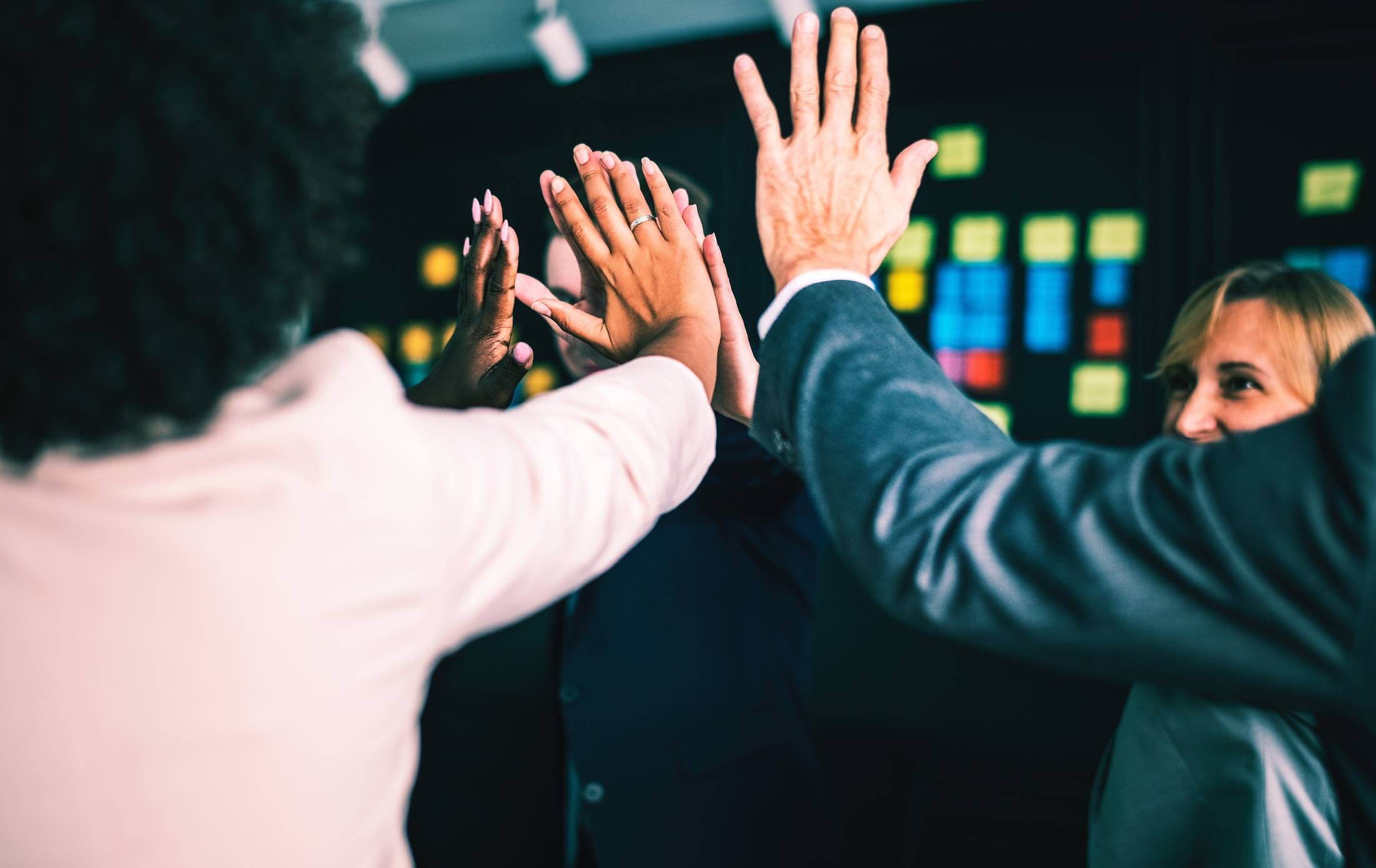 Several people in an office setting high fiving